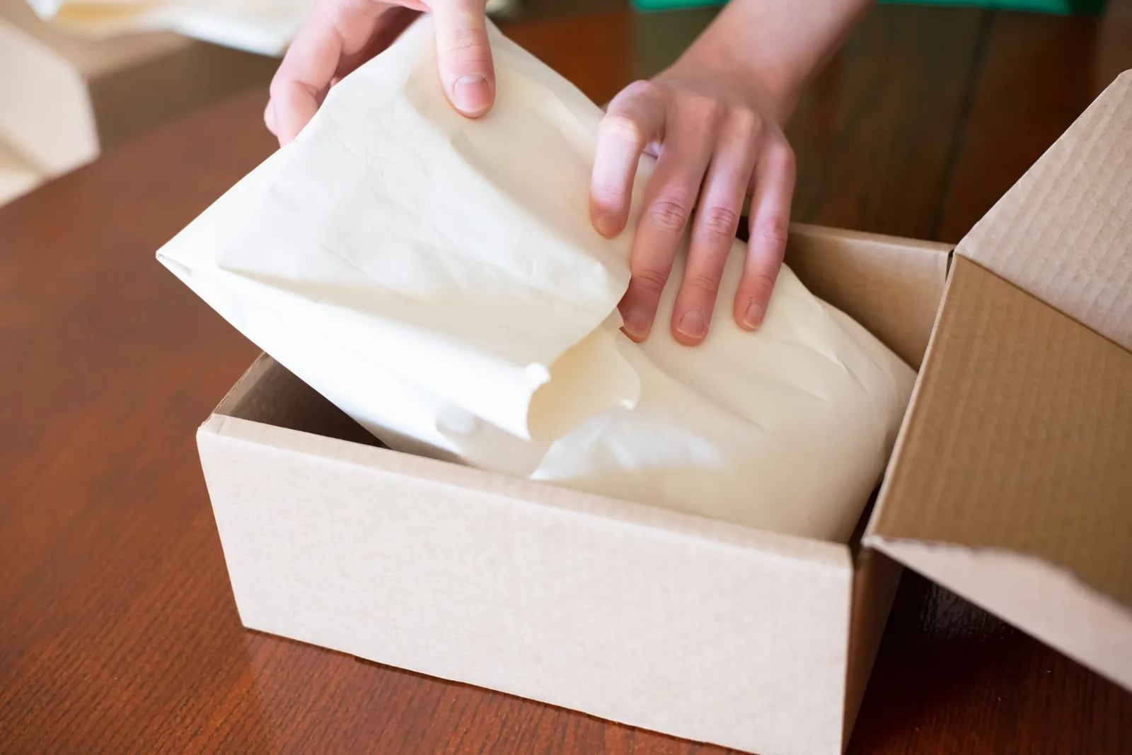 Hands packing an order into a cardboard box